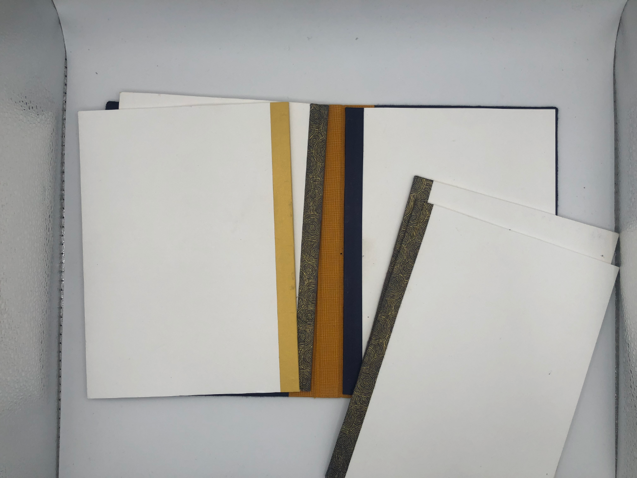 Carnet Flip Flap ouvert à plat : les dos dorés alignés, la toile ocre de la couvrure au centre