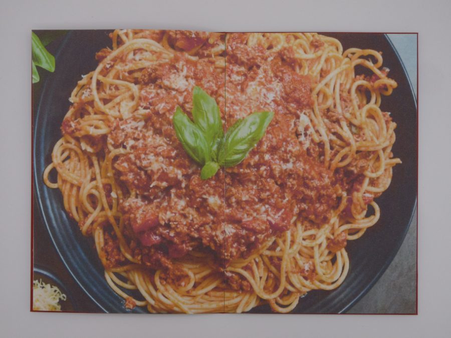 Double page pleine : spaghetti bolognaise et basilic dans une assiette sombre